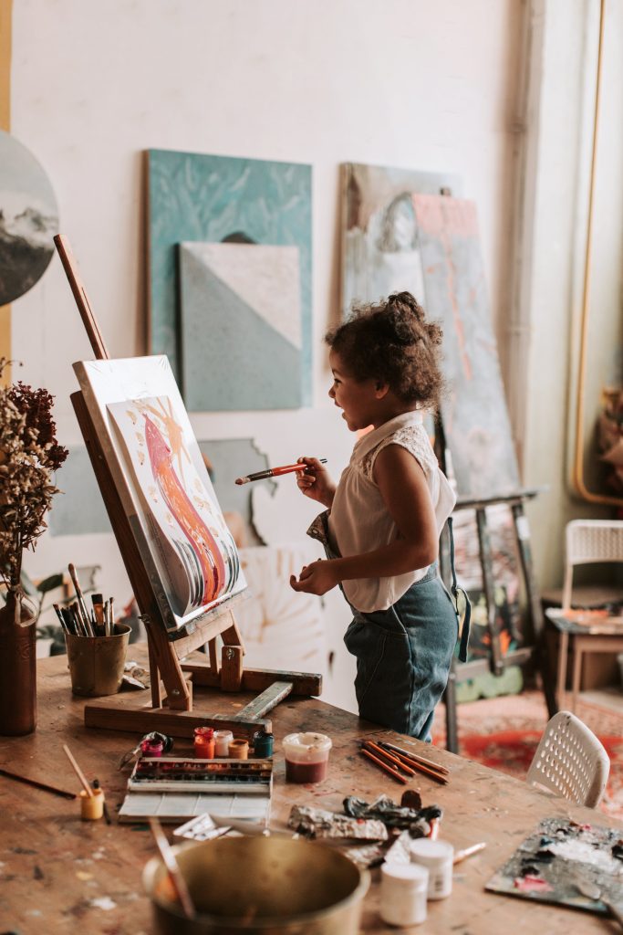 A child joyfully painting, to illustrate the aspect of art and child development in this article 