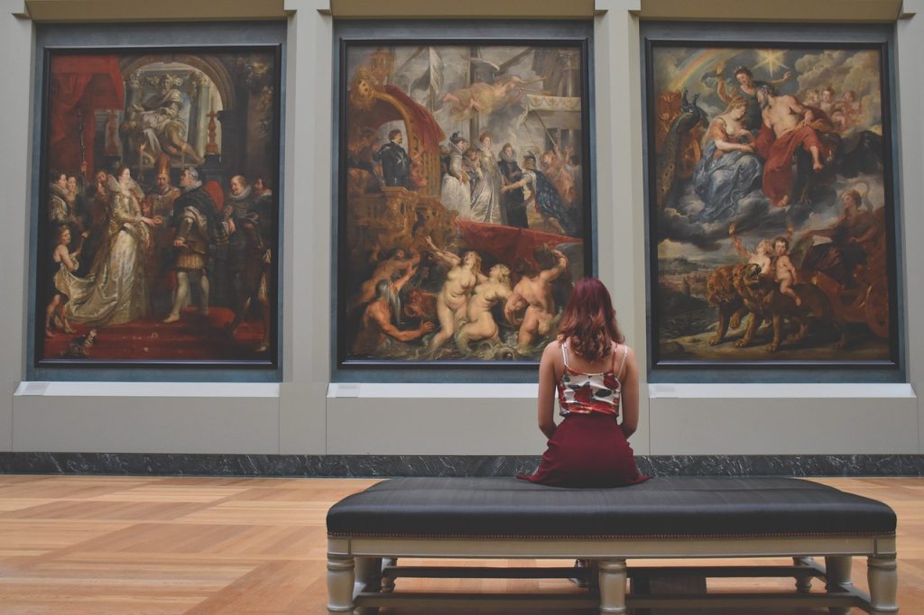 An artistic picture of a women looking at a museum work of art