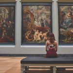 An artistic picture of a women looking at a museum work of art