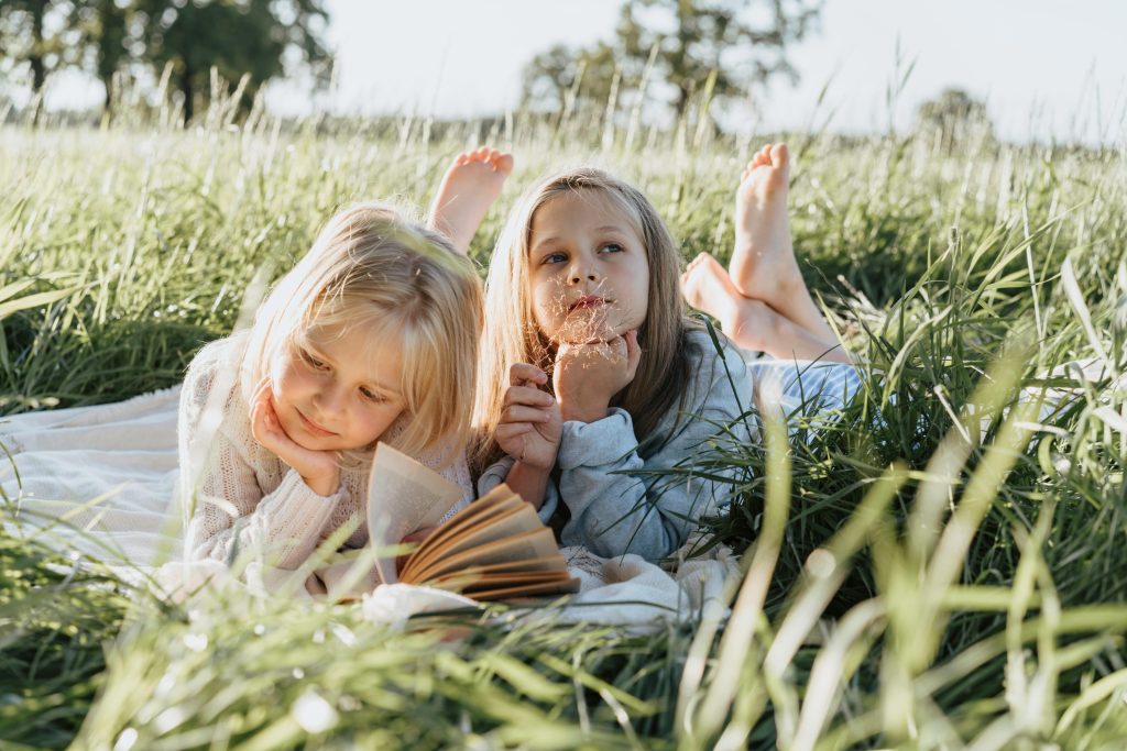 an image of 2 kids in a sunny green field, reflecting an Eco-therapy setting 